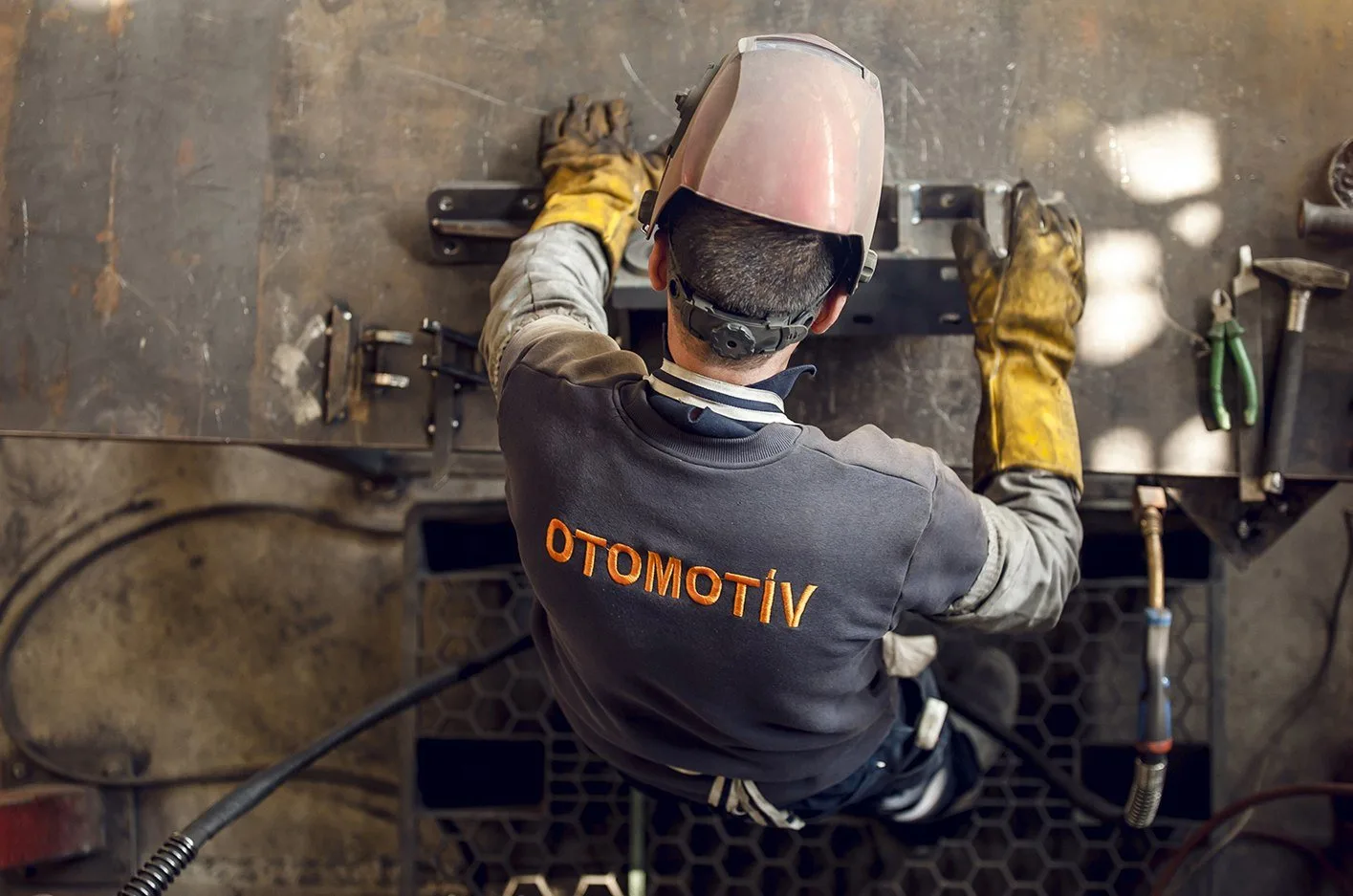 Kaynak maskeli işçi yukarıdan çekilmiş, otomotiv üretim hattı fotoğrafı