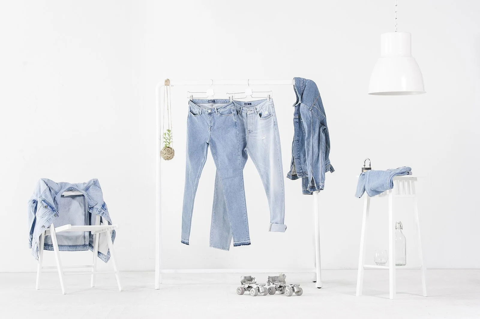 Askıda ve sandalyede kot pantolon ve ceketler, beyaz fonda denim ürün fotoğrafı