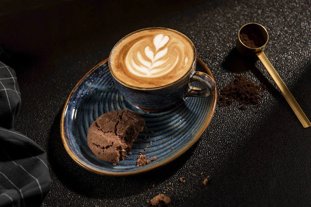Latte art'lı kahve ve kurabiye, koyu zemin üzerinde mavi fincan, kafe fotoğrafı