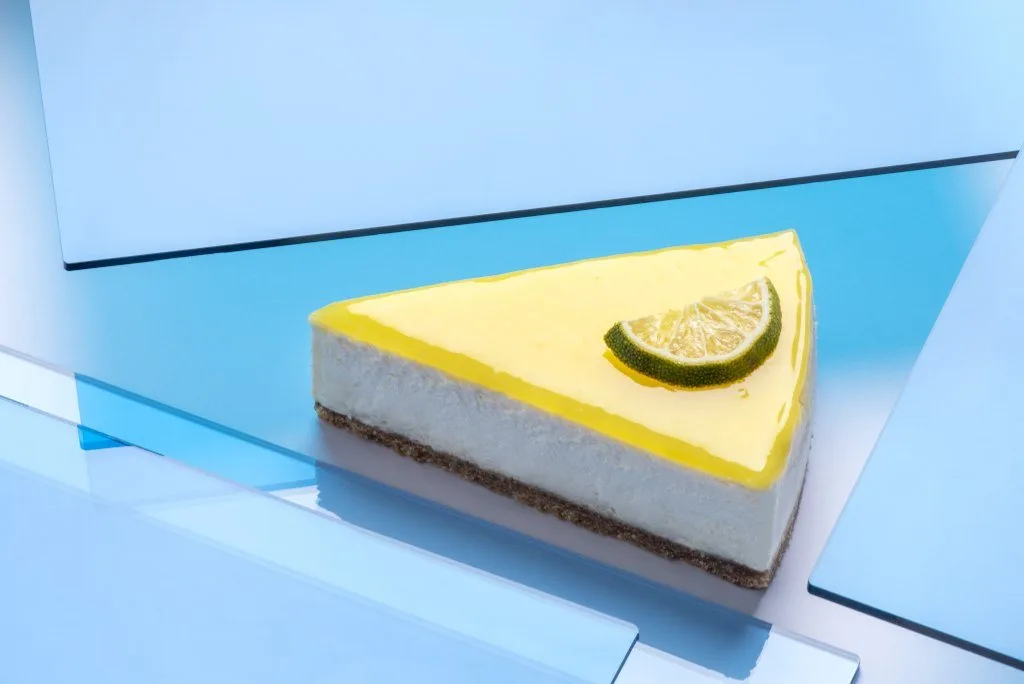 Mavi cam yüzeyler üzerinde limonlu cheesecake dilimi, pastel zemin tatlı fotoğrafı