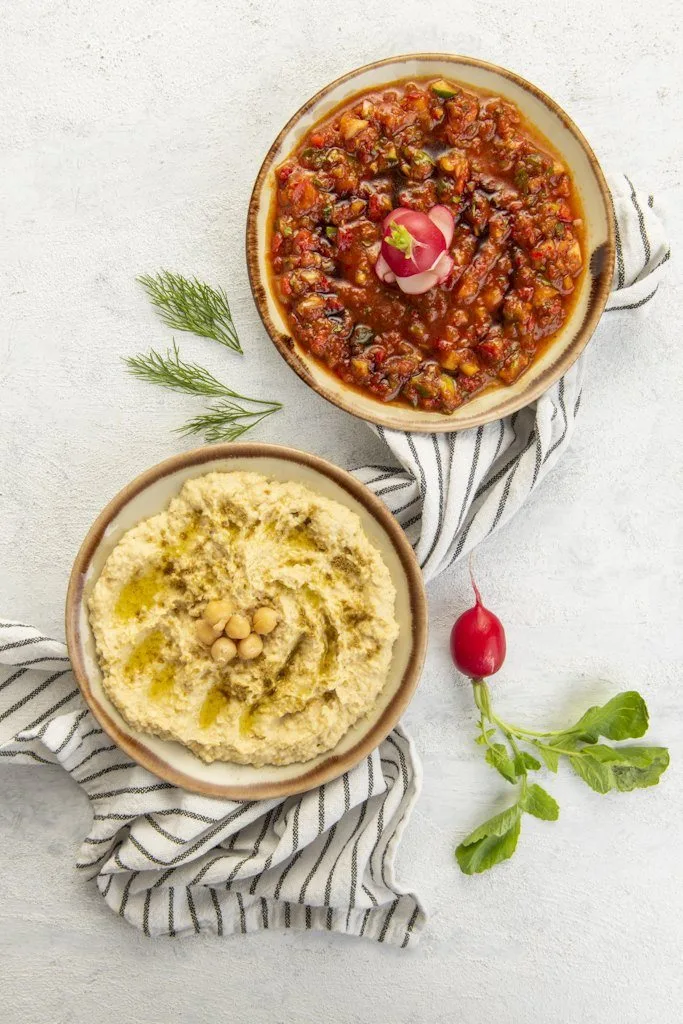 Fırında yemek ve humus tabakları, keten örtü üzerinde yukarıdan menü fotoğrafı