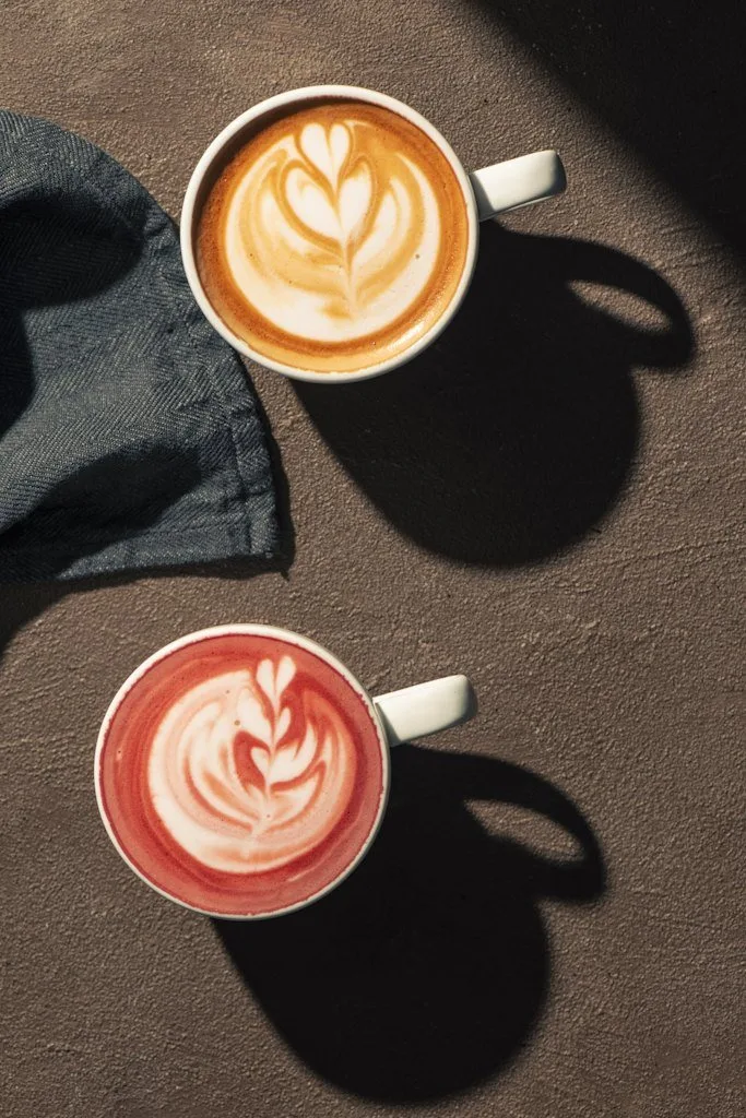 Latte art'lı iki kahve fincanı, koyu zemin üzerinde yukarıdan kafe fotoğrafı